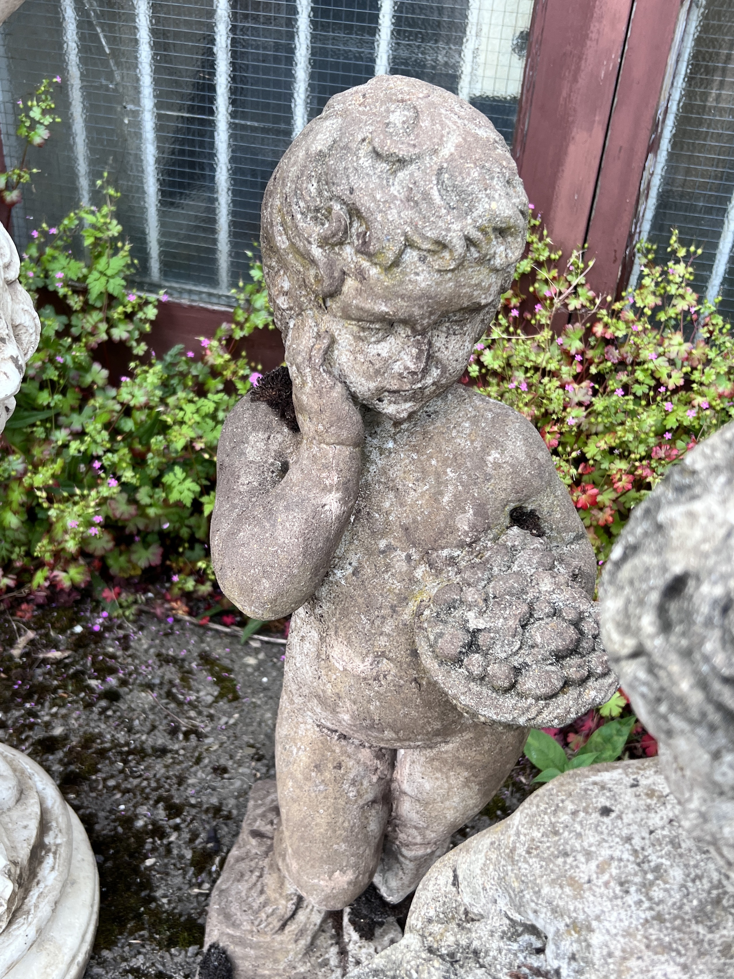 A pair of reconstituted stone garden ornaments, cherubs with fruit baskets, height 72cm